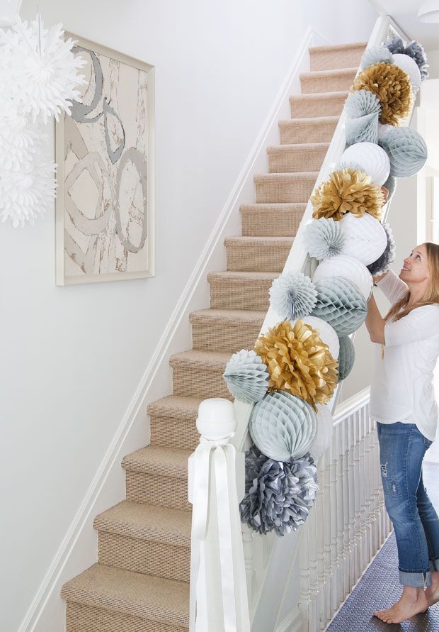 a woman standing next to a staircase decorated with pom - poms and balls