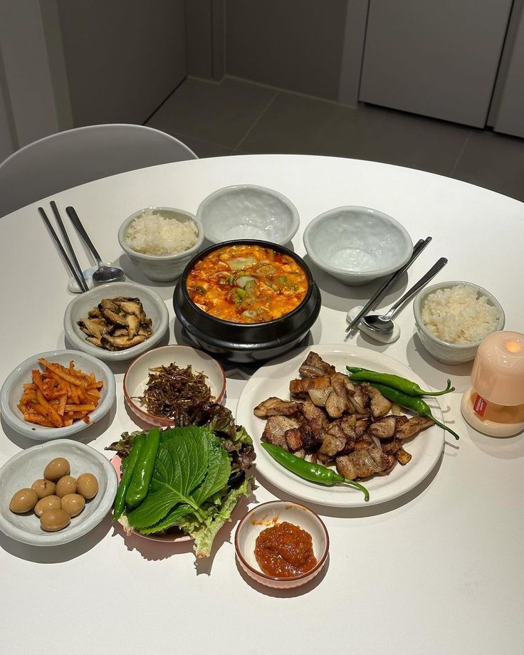 a white table topped with bowls and plates filled with different types of food on top of it