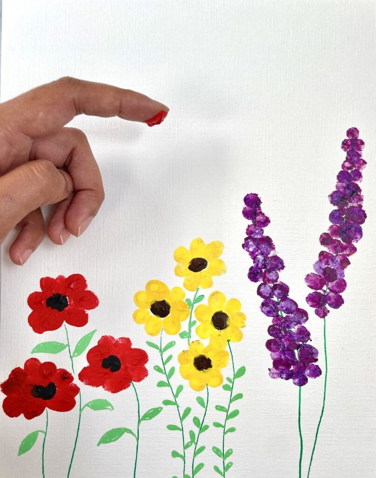 someone is painting flowers on a piece of paper