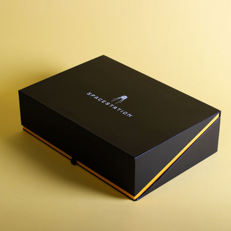 a black box with gold trim on the inside and bottom that has a white arrow in it