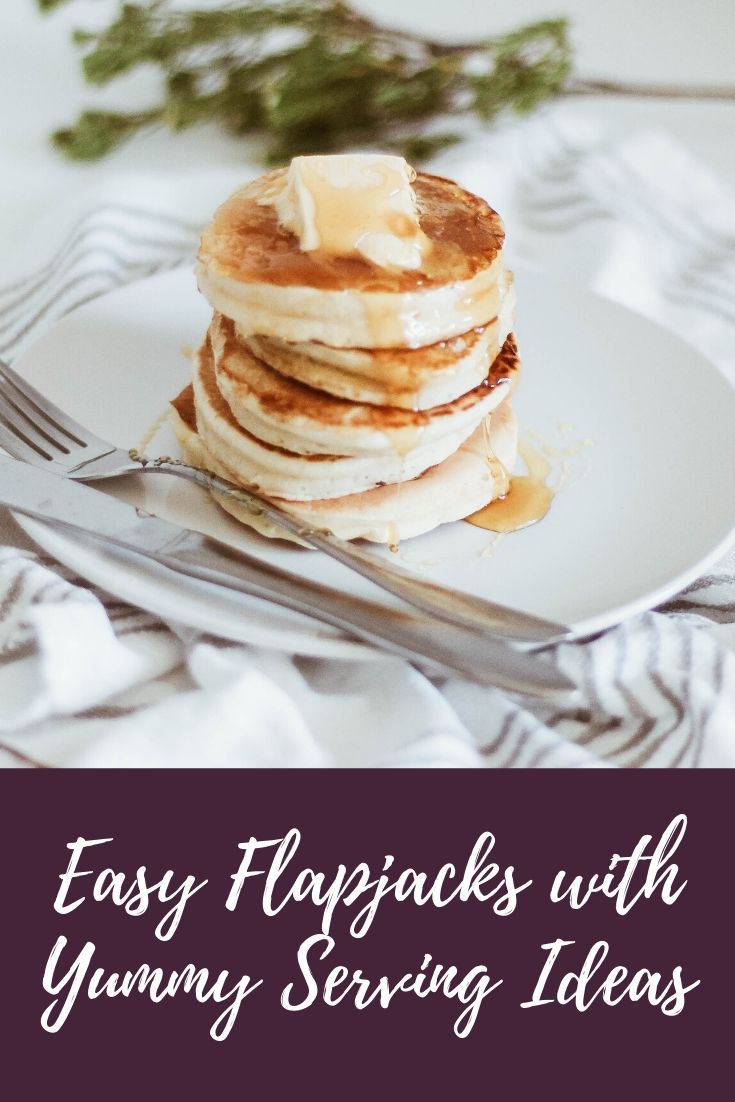 pancakes with yummy toppings on a white plate next to a fork and knife