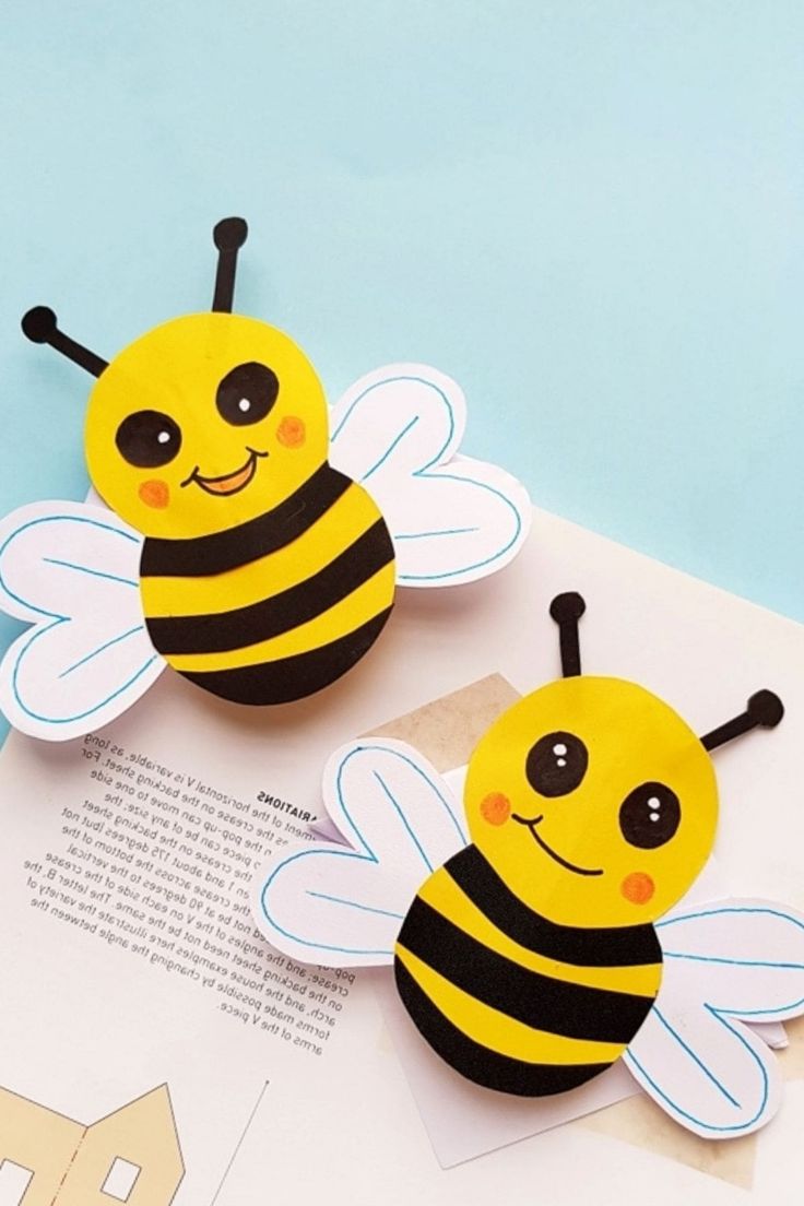 two paper bees sitting on top of an open book