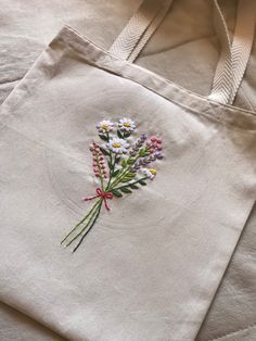 a white tote bag with flowers embroidered on it