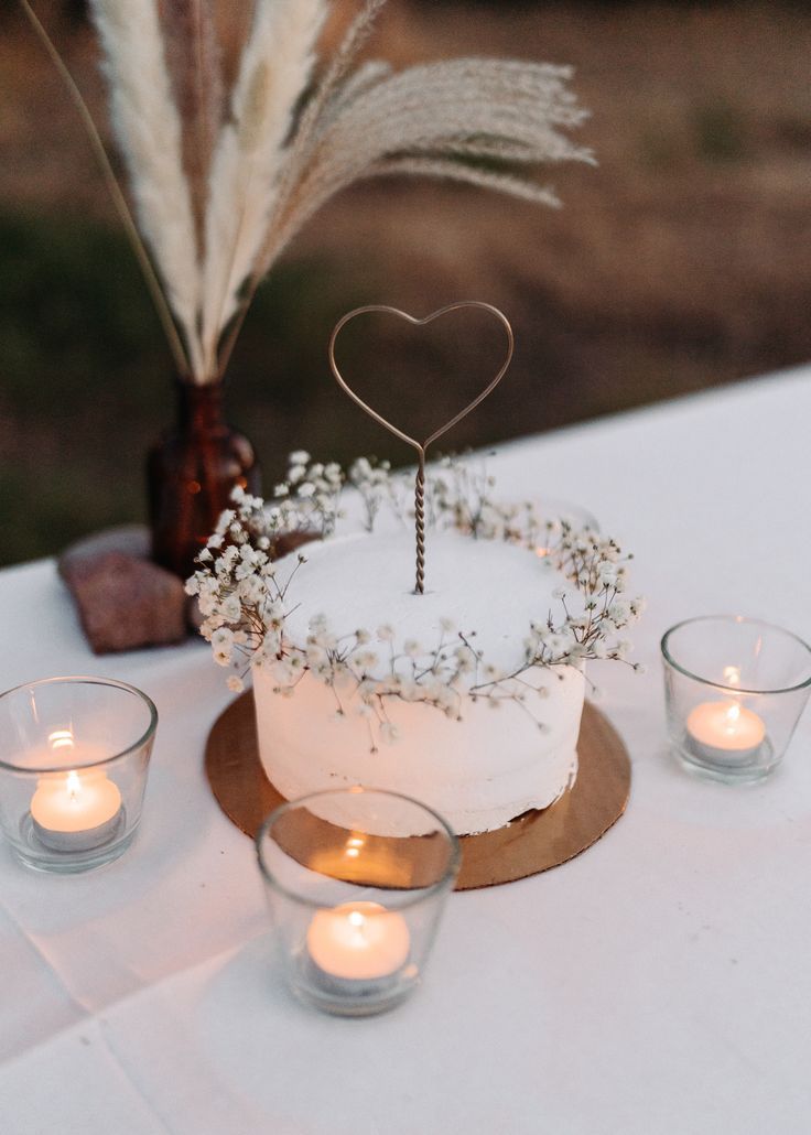 a white cake sitting on top of a table next to candles