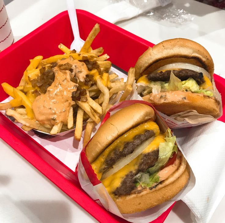 two cheeseburgers and fries on a red tray