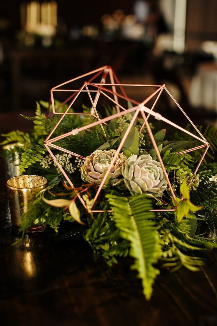 an arrangement of succulents and greenery on a table