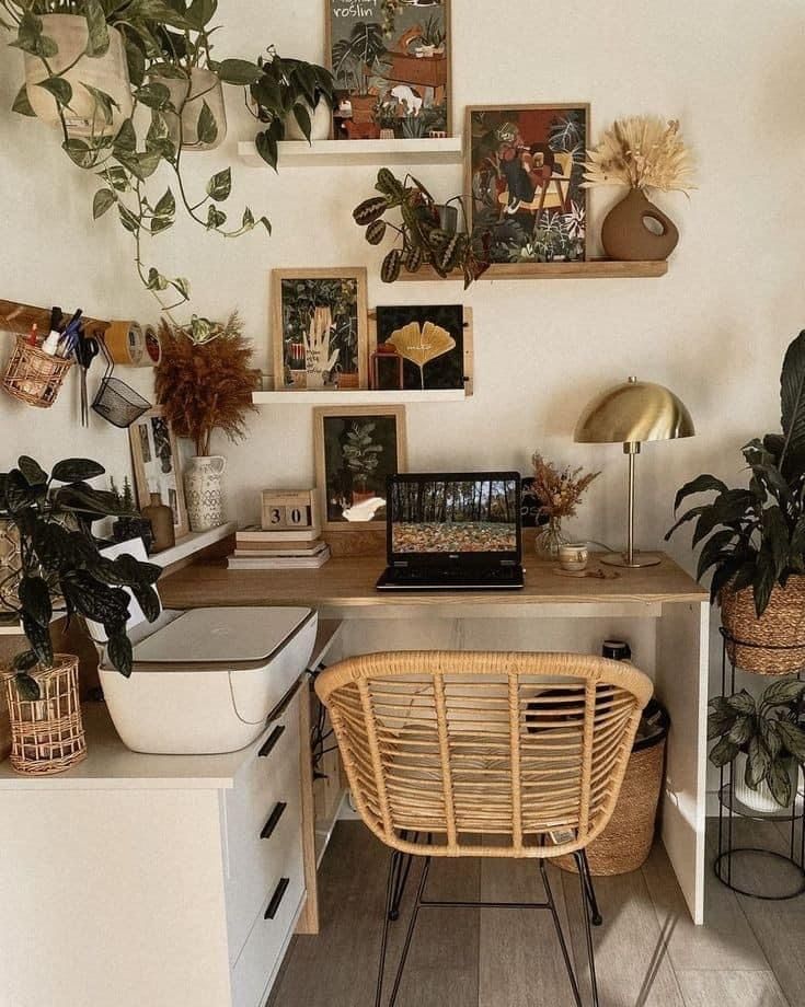 a home office with plants and pictures on the wall above it, along with a wicker chair