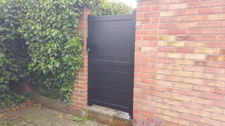 a black door is open in front of a brick wall with ivy growing on it