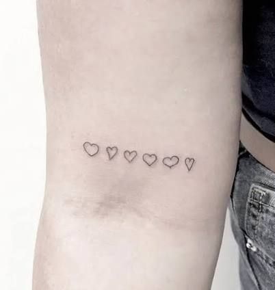 a woman's arm with four small hearts on the left side of her arm