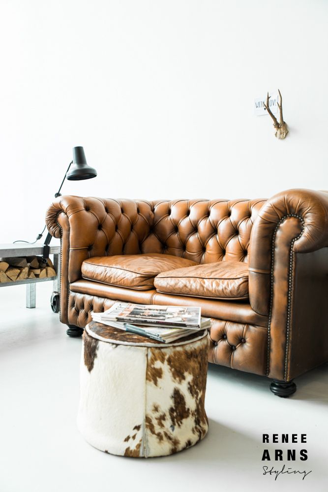 a brown leather couch sitting in a living room next to a table with a magazine on it