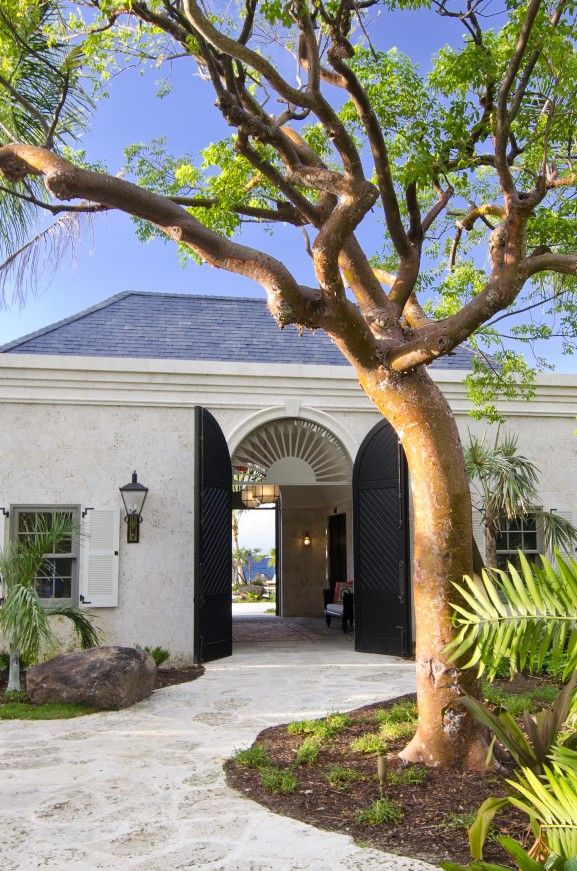 the entrance to a house with an arched doorway and black shutters on both sides