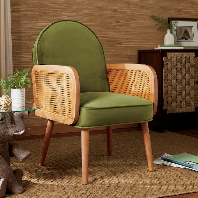 a green chair sitting on top of a wooden floor next to a table with a potted plant