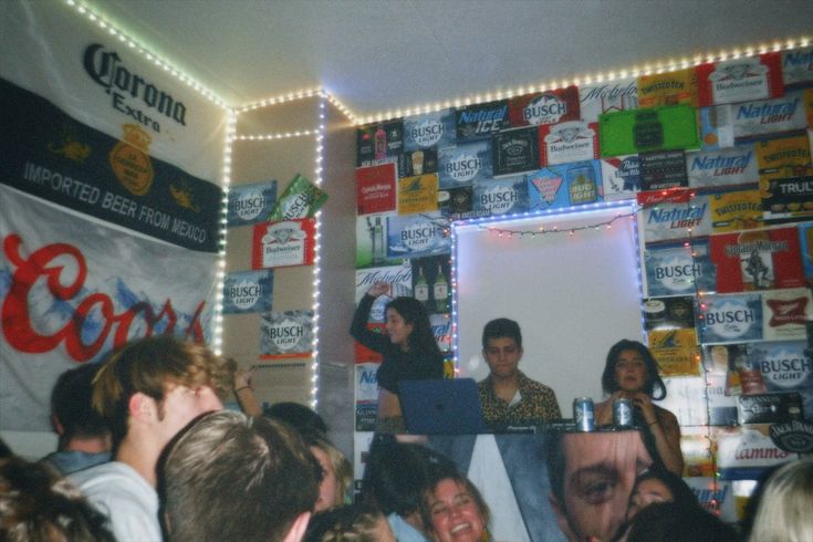 a group of people standing in front of a wall covered with coca - cola signs