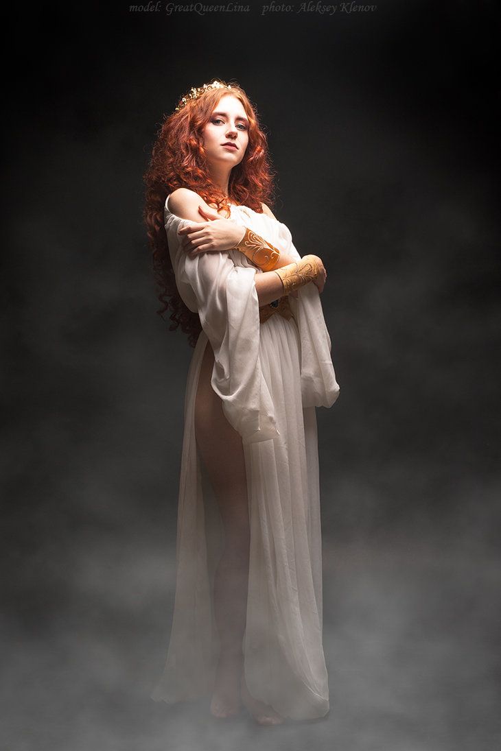 a woman with long red hair wearing a white dress and holding a teddy bear in her arms