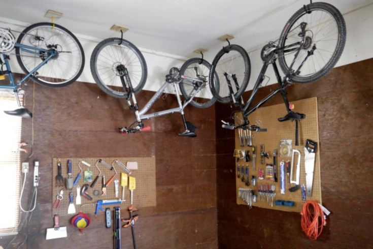 three bikes are hanging from the ceiling in a room with tools and other things on it