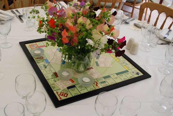 a vase filled with lots of flowers on top of a table covered in wine glasses