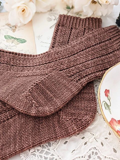 a brown knitted sweater next to a white lace doily with flowers on it