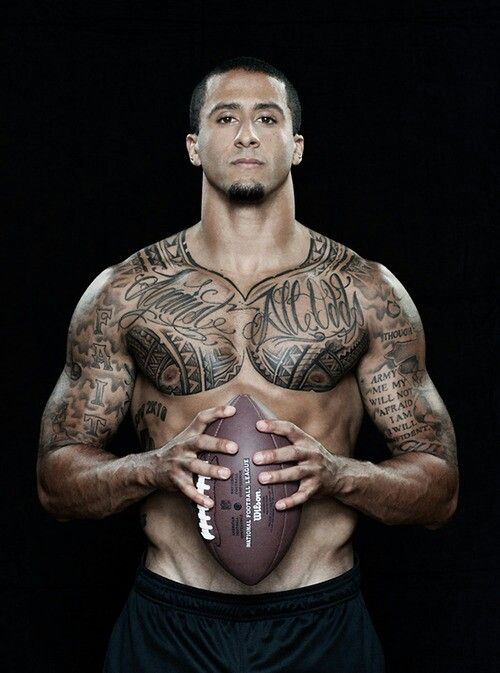 a man with tattoos holding a football