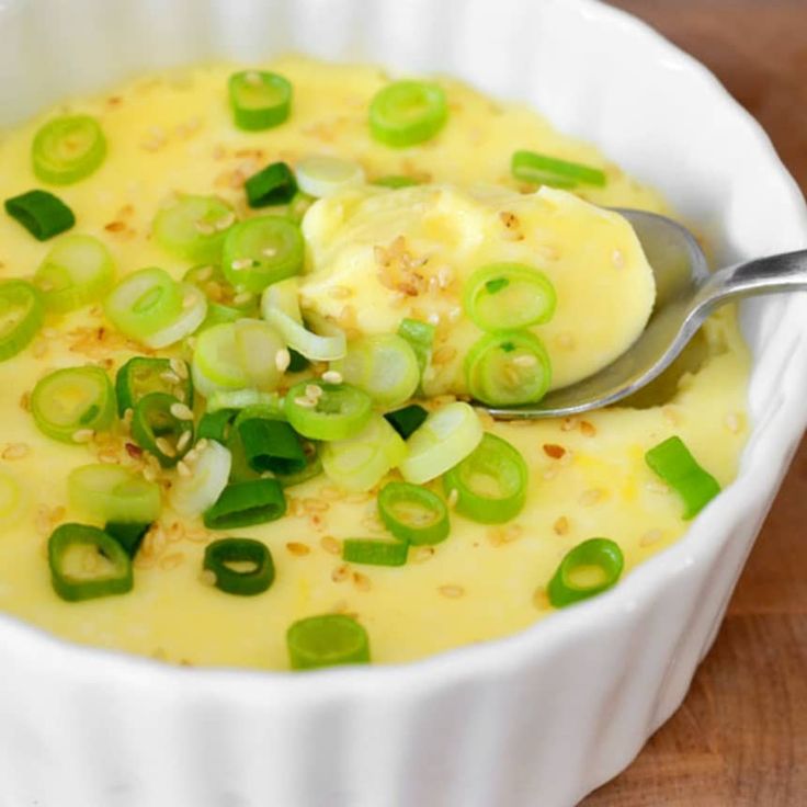 a white bowl filled with cheese and green onions