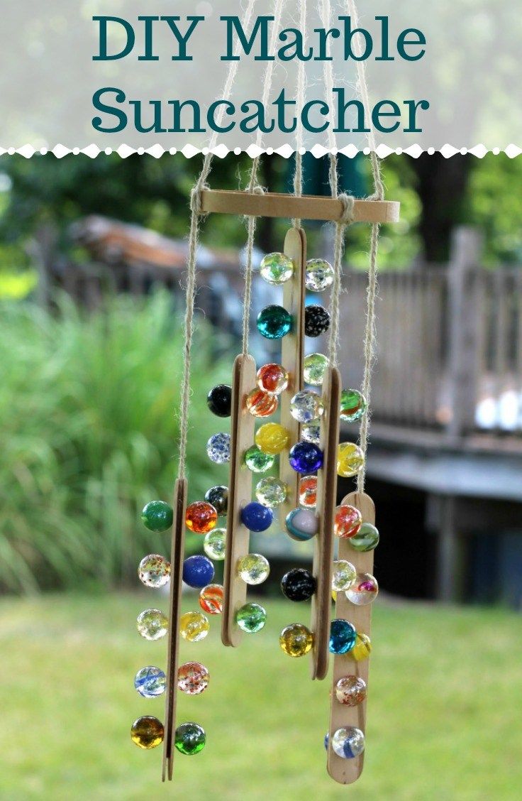 a wind chime made out of marbles and wood sticks with text overlay that reads diy marble suncatcher