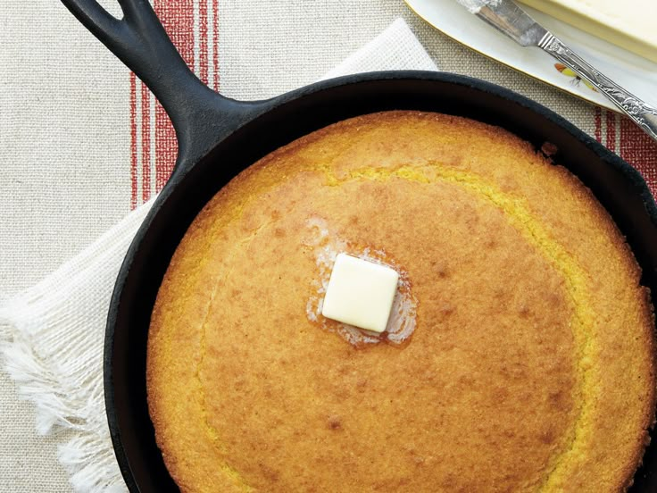 a pan with some food in it on top of a table next to a knife and fork