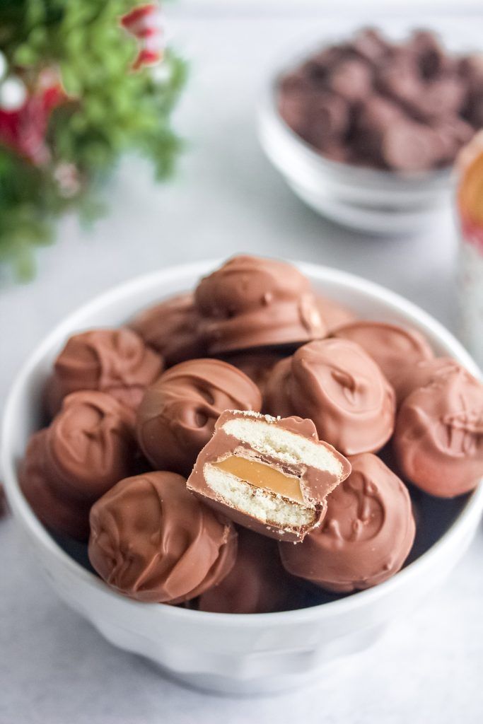 a bowl filled with chocolate covered donuts on top of a white table next to other desserts