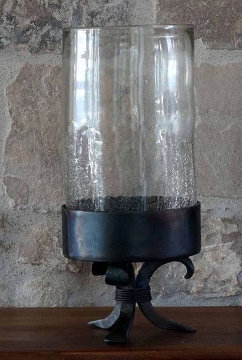 a glass jar with some sand in it on a wooden table next to a stone wall