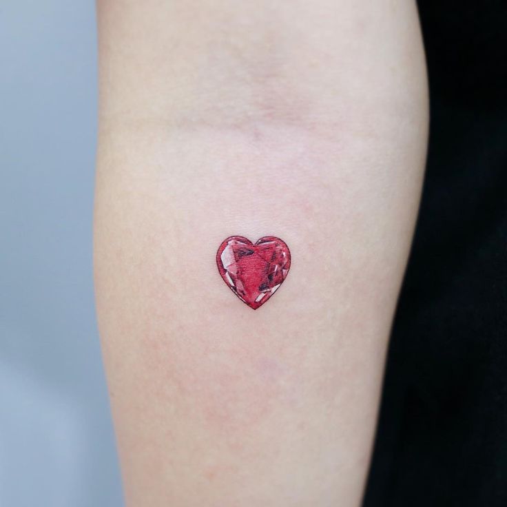 a red heart tattoo on the left arm