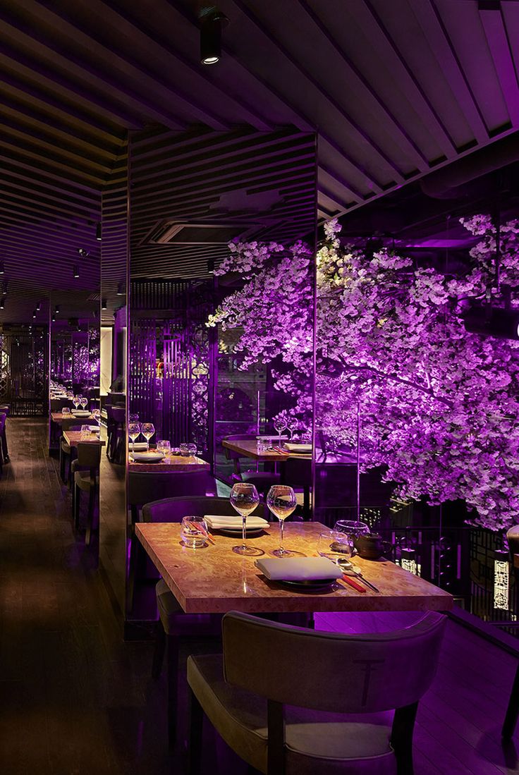 a dining room with purple lighting and wooden tables