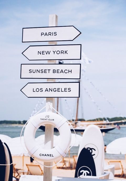 there are many signs on the beach pointing to different places in paris, new york, sunset beach and los angeles