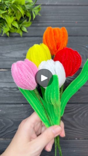 someone is holding up some flowers made out of crepe paper and yarns