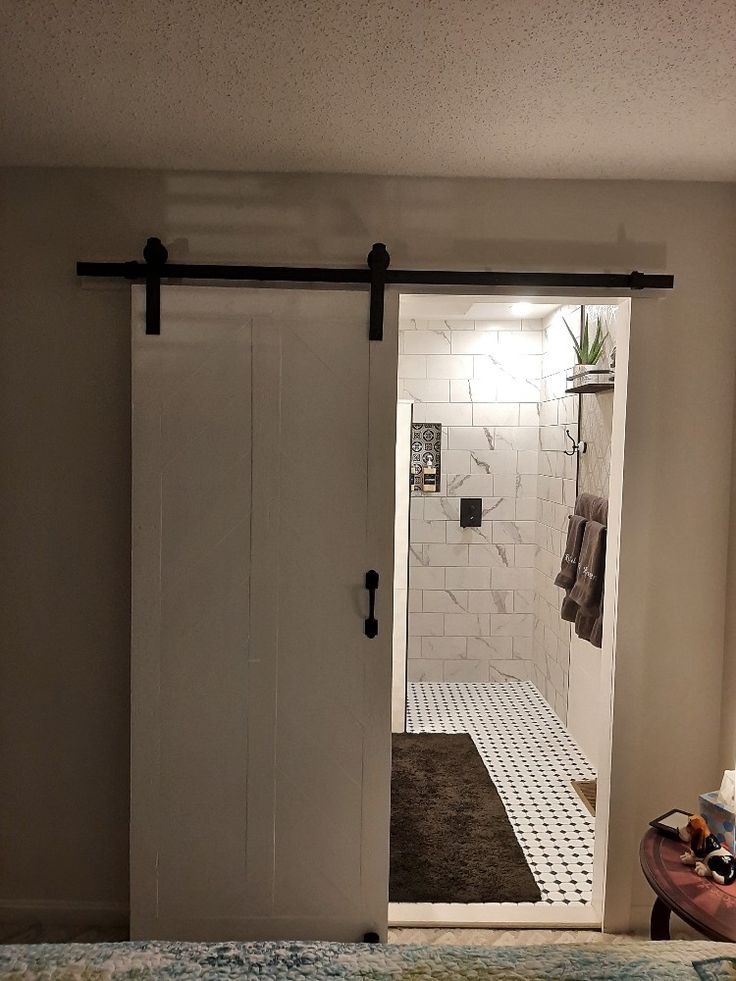 an open door leading to a bathroom with a rug on the floor and a towel rack