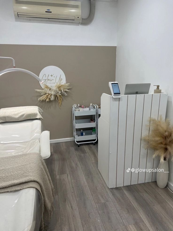 a white bed sitting next to a wall mounted air conditioner in a room with wood flooring