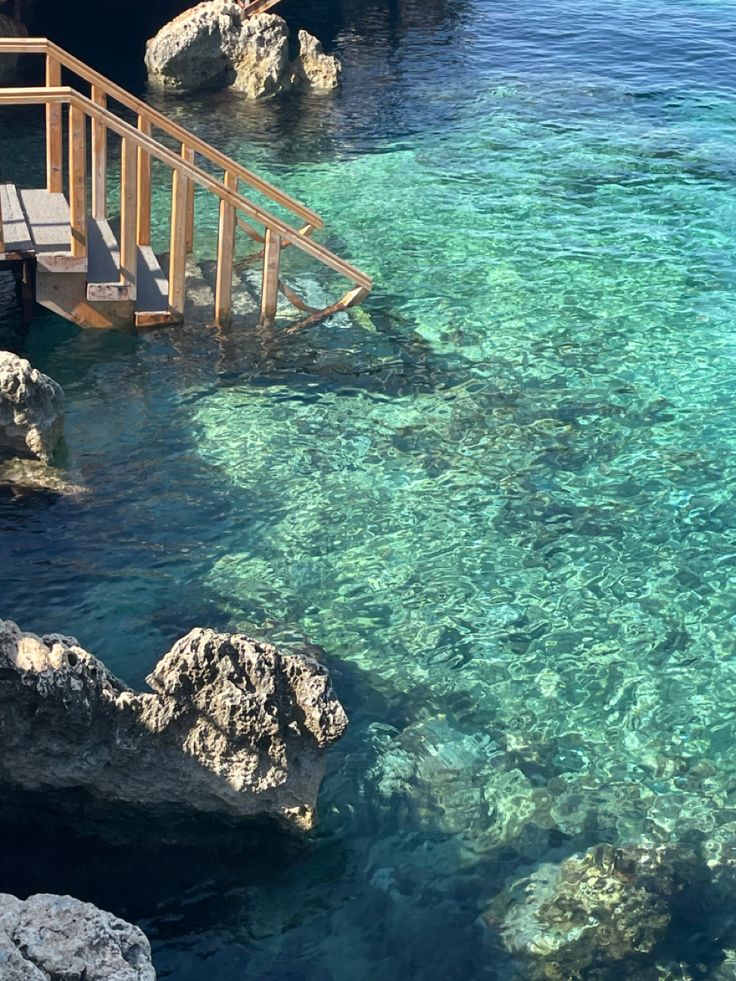 the water is crystal blue and clear, with steps leading down to the beach area