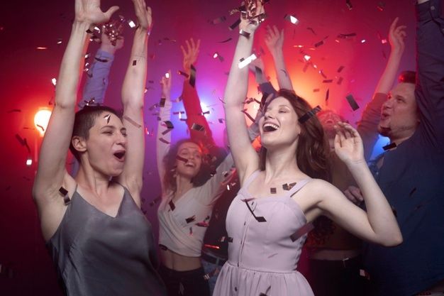 two women are dancing with confetti in the air