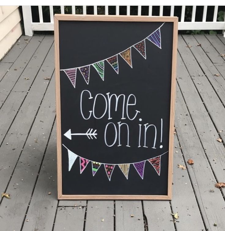 a chalkboard sign that says come on in front of a porch with bunting