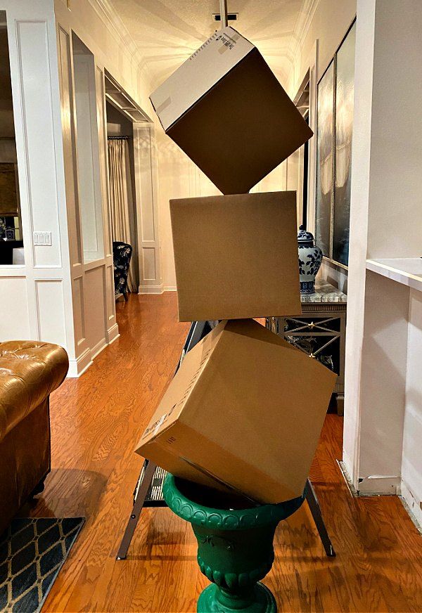 several boxes stacked on top of each other in the middle of a living room with hard wood floors