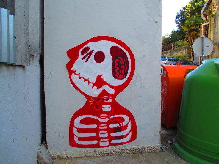 a red and white sticker on the side of a building next to trash cans