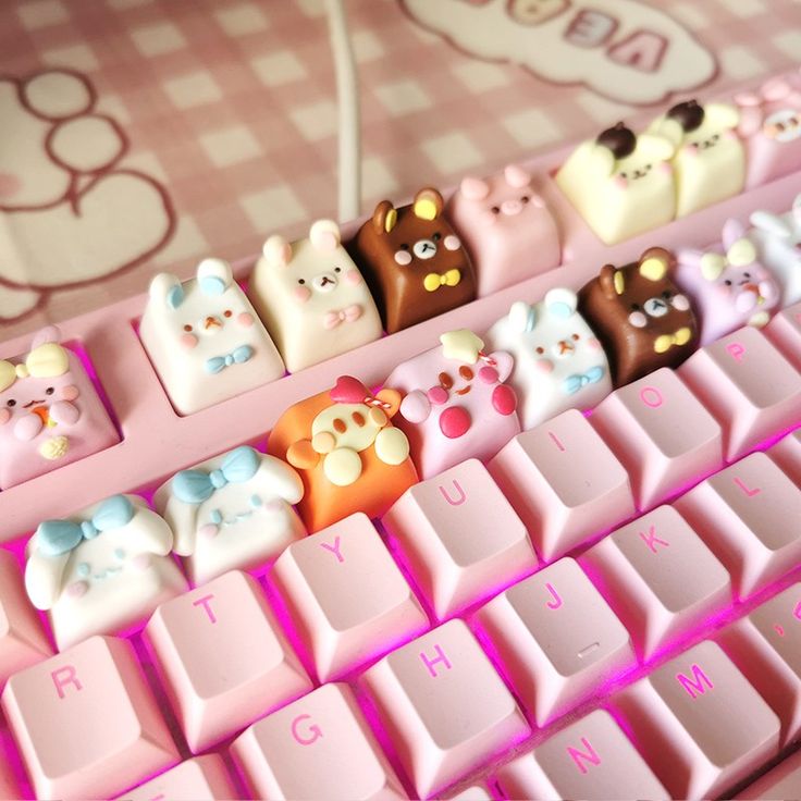 there are many small toy animals sitting on the keys of a computer keyboard, which is decorated with pink and white squares