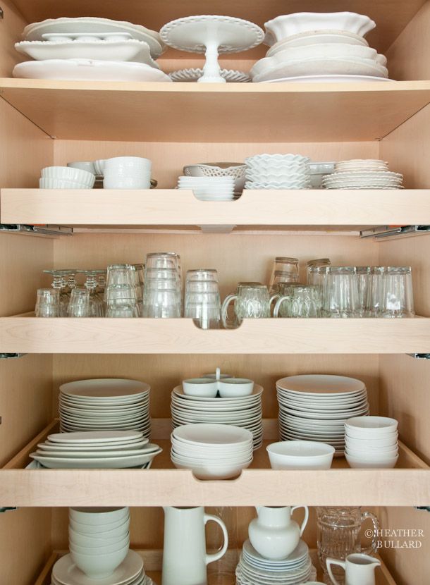 an open cabinet filled with white dishes and plates on top of wooden shelves next to each other