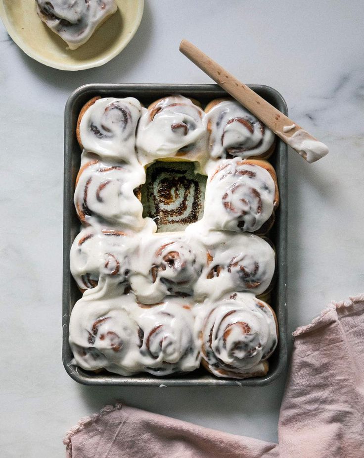 a pan filled with cinnamon rolls covered in icing