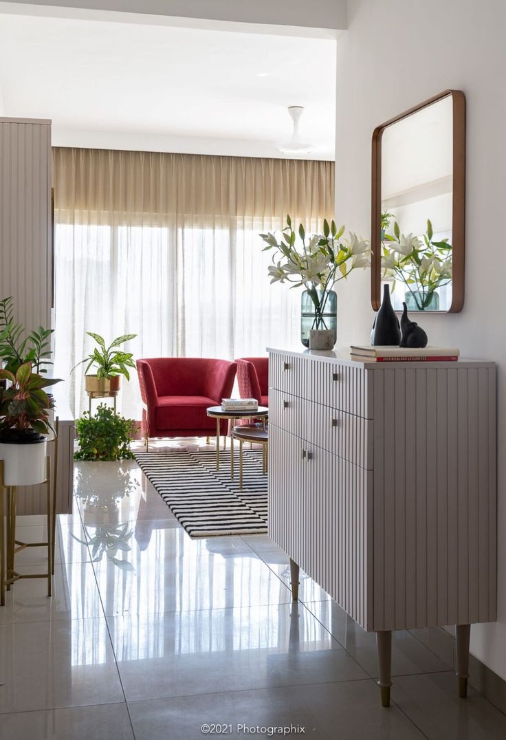 a living room filled with furniture and flowers in vases on top of a dresser