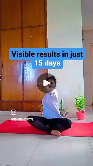 a woman sitting on top of a red yoga mat in front of a wooden door