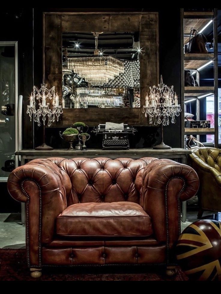 a brown leather chair sitting in front of a bar with chandelier hanging from the ceiling