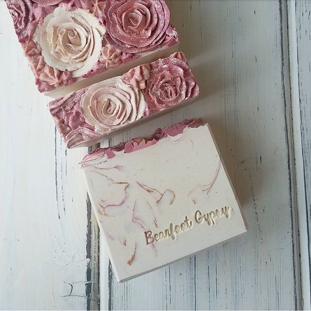 three soap bars with pink roses on them sitting next to each other in front of a white wooden background