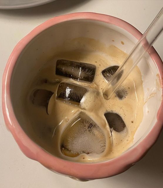 a pink bowl filled with liquid and ice cubes