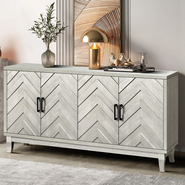 a sideboard with two doors and a vase on top, in front of a mirror