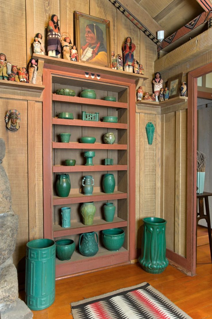 a room filled with lots of green vases on top of wooden shelves next to a rug