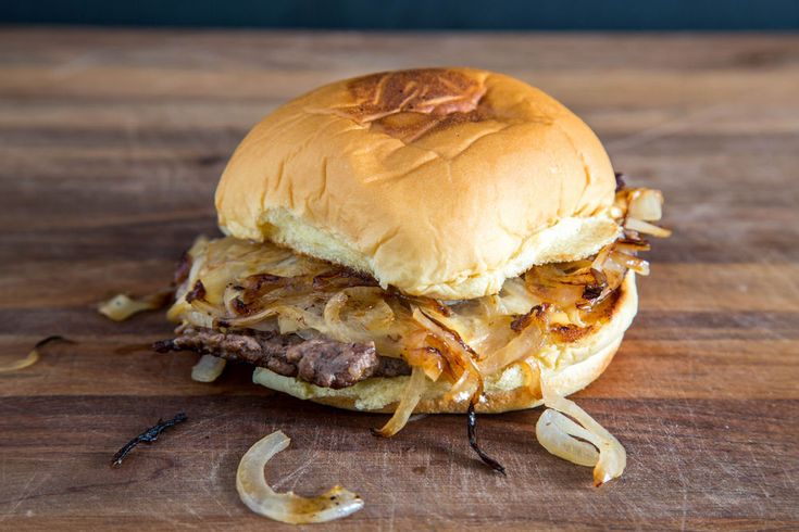 a pulled pork sandwich sitting on top of a wooden cutting board