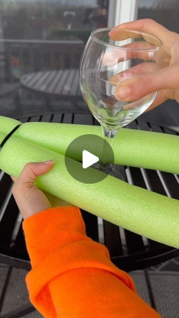 a person holding a wine glass over a green piece of paper that is on top of a grill